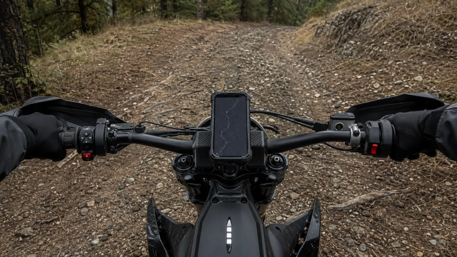 Cockpit einer E-Enduro im Gelände mit Smartphone in der Lenkerhalterung