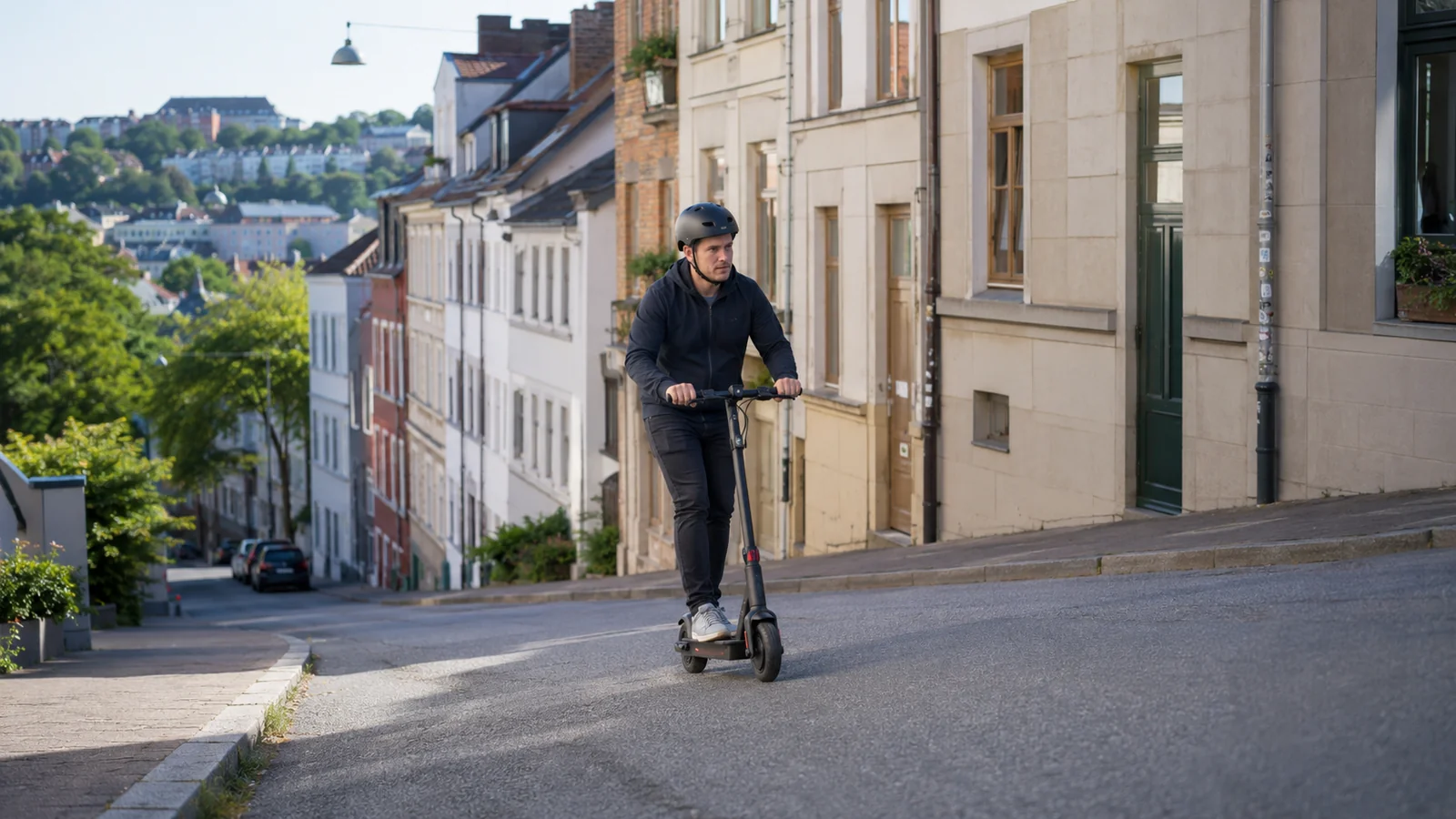 Fahrer mit Helm fährt auf einem E-Scooter eine steile Straße bergauf