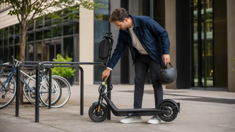 Mann schließt seinen E-Scooter an einem Fahrradständer an und hält einen Helm