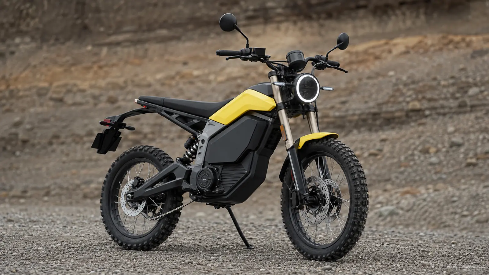 NIU XQi3 Elektro-Scrambler in Gelb-Schwarz mit Straßenausstattung auf Schotter