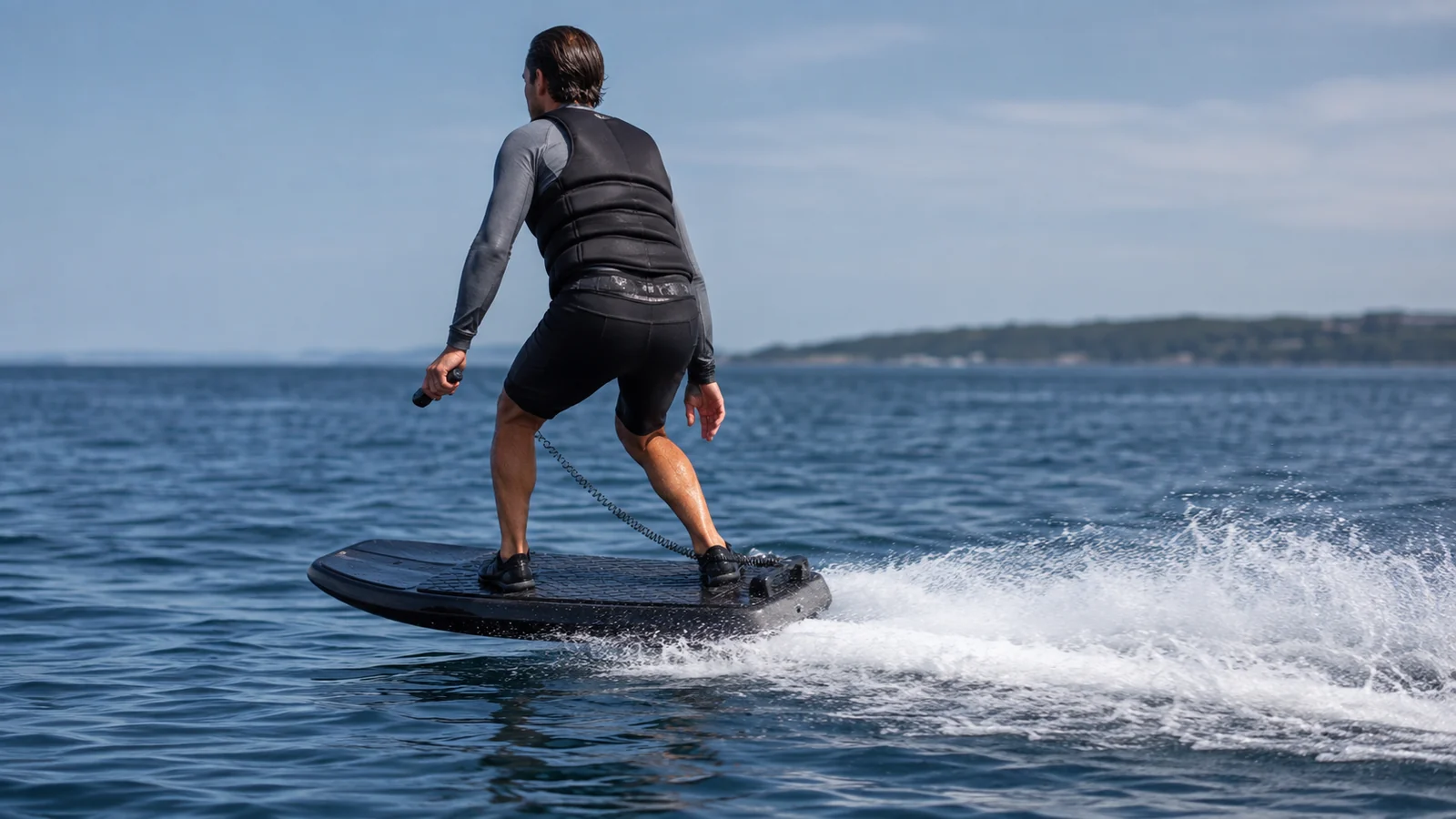 Elektrisches Jetboard mit Jet-Impeller-Antrieb gleitet auf dem Wasser, Fahrer mit Handregler