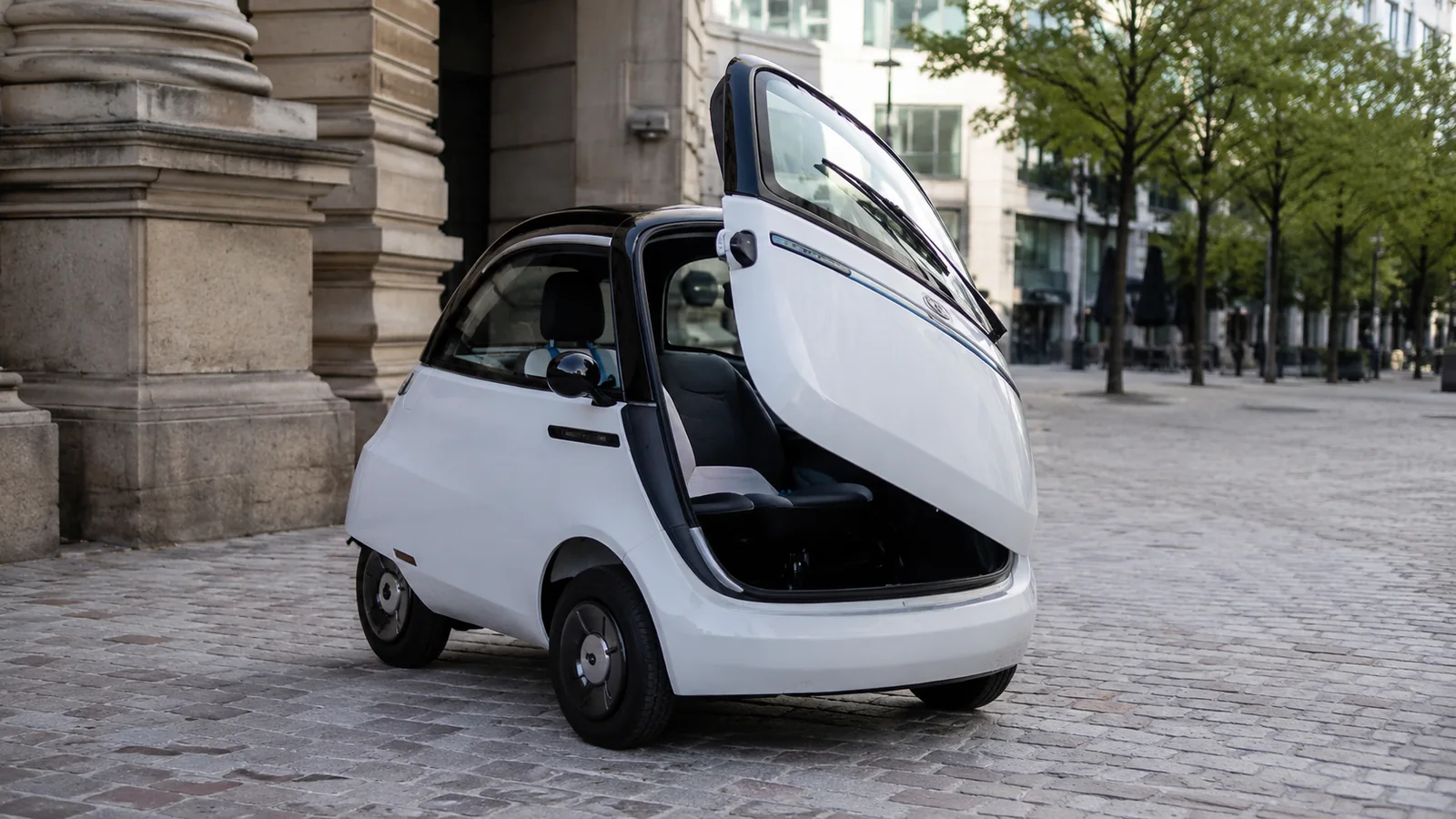 Microlino Elektro-Leichtfahrzeug mit geöffneter Fronttür im Stadtverkehr